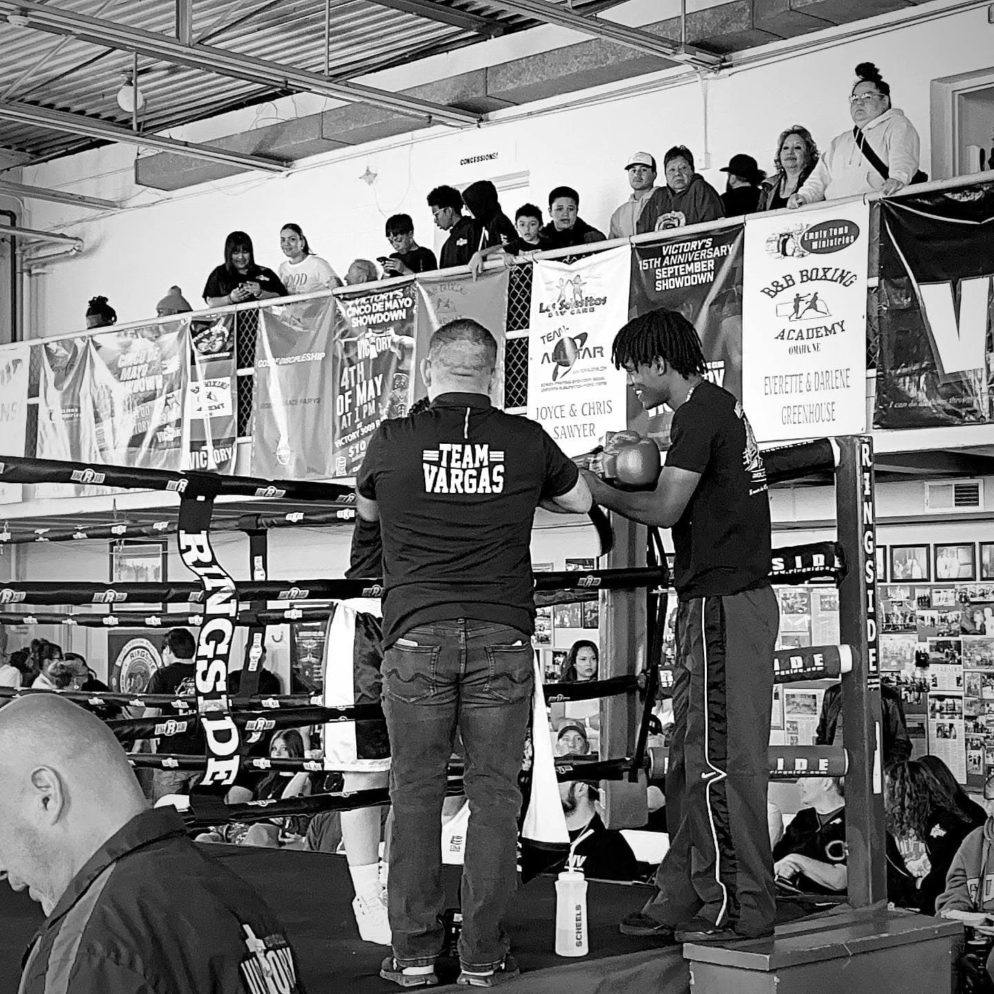 A coach working the mitts with a fighter under the Team Vargas banner
