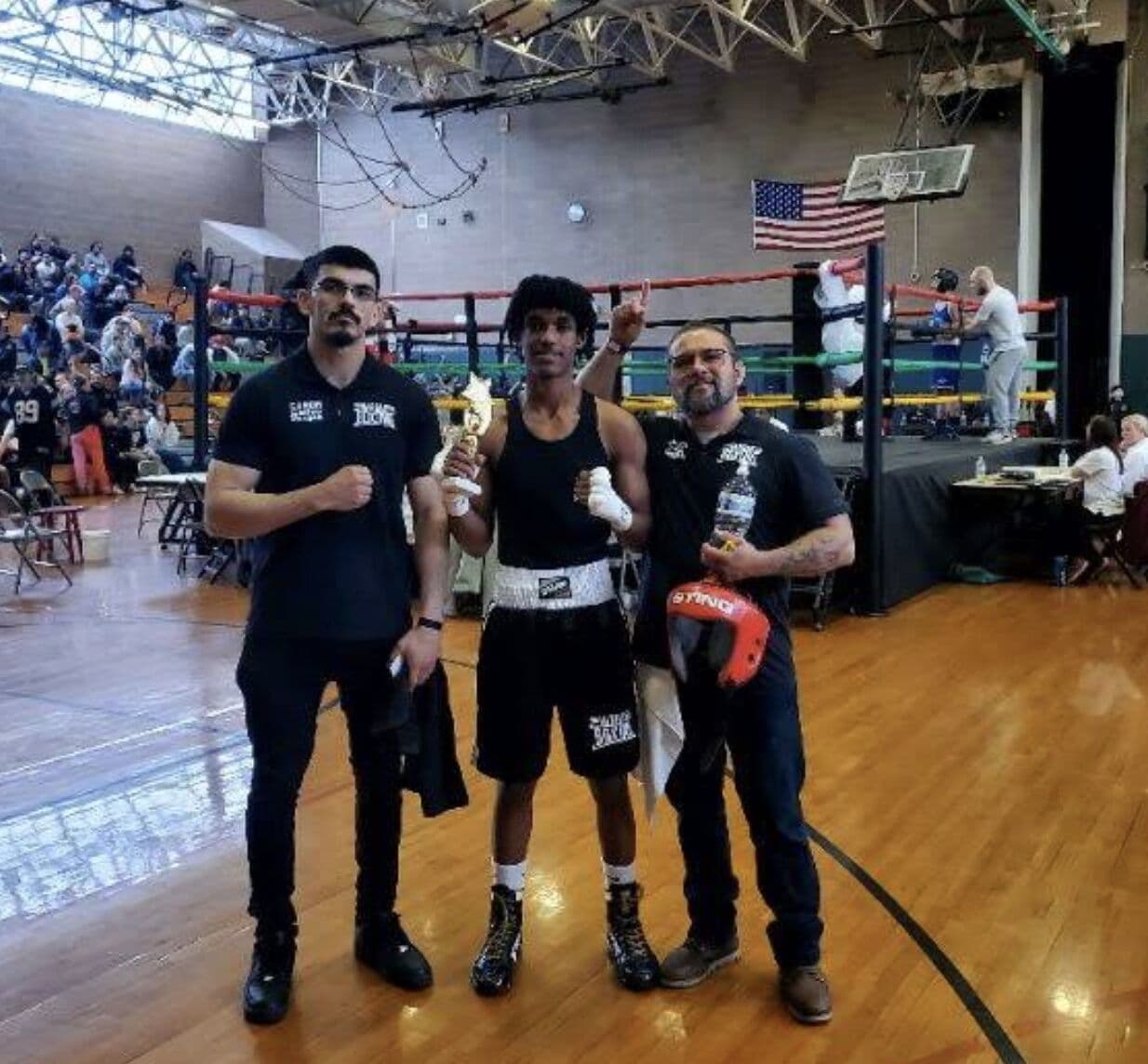 A Vargas fighter on the tournament podium with his coaches and his trophy